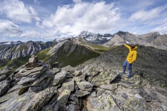 Mountaineer points into the distance, at the summit of Kastenegg, view of picturesque mountain