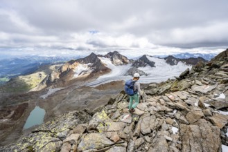 Mountaineer with helmet on a rocky hiking trail, in high mountain landscape, view of blue glacial
