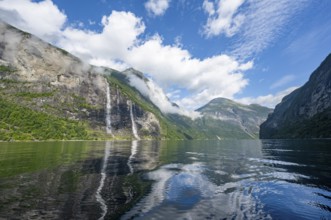 Atmospheric fjord landscape with waterfall The Seven Sisters, Geirangerfjord with reflection, Møre