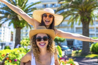 Two cheerful female friends are having fun during summer vacation, wearing sunglasses and straw