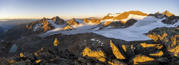 Mountaineers in front of a picturesque high mountain landscape at sunrise with alpenglow, blue