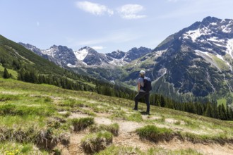 Hiker gazes at majestic snow-capped mountain peaks of the Alps in Kleinwalsertal, Austria, Europe