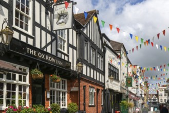 Bunting flags decorating buildings in historic street, The Ox Row Inn and shops, Butcher Row,
