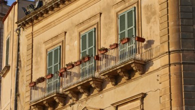 Detail of the façade of a historic building in warm sunlight with balconies, Ortigia Island, Isola