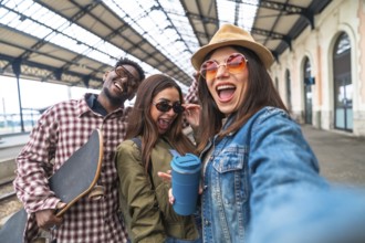 Group of young cheerful best friends having fun taking a selfie at the railway station before