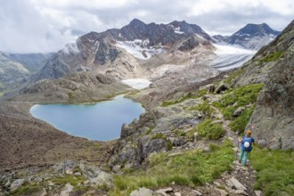 Mountaineer on hiking trail in dramatic high mountain landscape, view of mountains with mountain