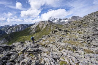 Mountaineer in boulder terrain, at the summit of Kastenegg, view of picturesque mountain landscape