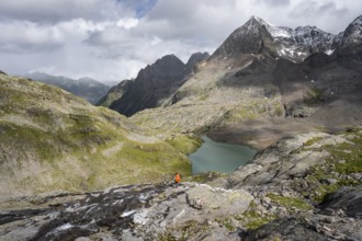 Mountaineer on a rocky hiking trail, view of the turquoise-blue mountain lake Großer Gradensee,