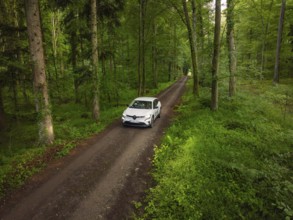 Car driving on a narrow forest path, surrounded by forest landscape, Deer E- CarSharing, Renault