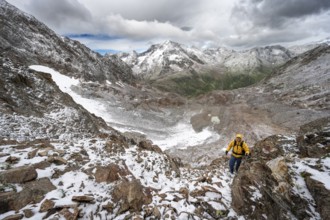 Mountaineer on a rope-secured climb in a steep rocky mountain landscape with fresh snow in summer,