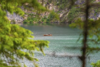 A small boat on a spacious, quiet lake surrounded by lush trees, Pragser Wildsee, South Tyrol,