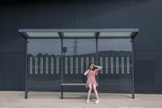 Portrait of a young woman waiting at a bus stop, Emilia-Romagna, Italy, Europe
