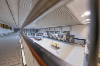 A side view of exhibits in an art gallery illuminated under a textured ceiling, historical art