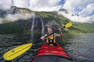 Kayak trip on the Geirangerfjord at the waterfall The Seven Sisters, Young man paddling in a kayak,