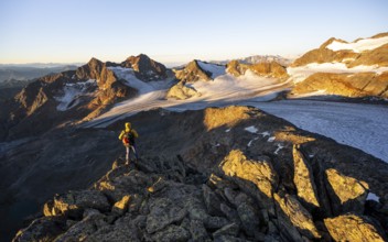 Mountaineers in front of a picturesque high mountain landscape at sunrise with alpenglow, glacier