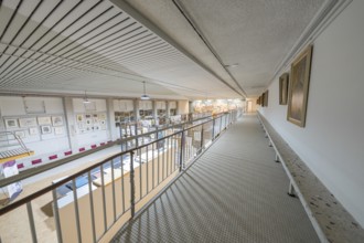 A wide corridor in a gallery with works of art on the walls and modern architectural design,