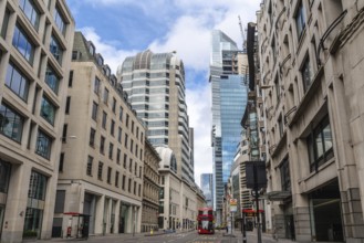 Red double decker bus driving on empty street surrounded by modern and historic buildings in city