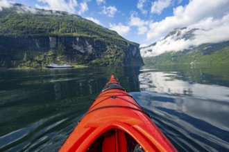Kayak trip on the Geirangerfjord, tip of a red kayak in the fjord with reflection, atmospheric