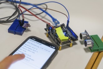 Smartphone with displayed data next to an electronic setup on a table, Youth Research Centre