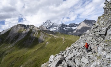 Mountaineer on steep rocky hiking trail, descent from the summit of Kastenegg, view of picturesque