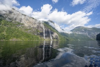 Atmospheric fjord landscape with waterfall The Seven Sisters, Geirangerfjord with reflection, Møre