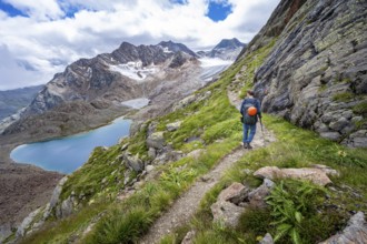 Mountaineer on hiking trail in dramatic high mountain landscape, view of mountains with mountain