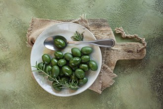 Chalkidiki olives, classic Greek green olive, on a plate, with a spoon, top view, no people