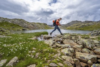 Mountaineer jumping from stone to stone, at a mountain lake in high mountain landscape at the Obere