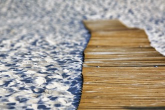 Empty wooden path on the sandy beach, wooden mat in the sand, barrier-free access,