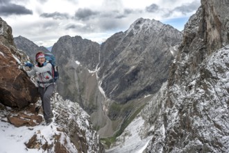 Female mountaineer on a rope-secured climb in a steep rocky mountain landscape with fresh snow in