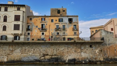 Houses with colourful facades and balconies along a stone seawall, boat trip around the island of