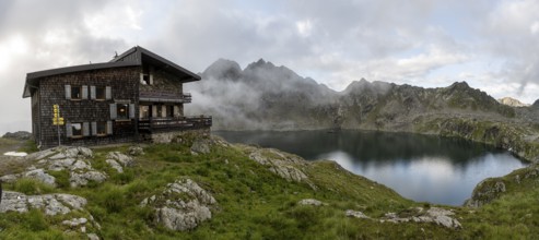 Mountain hut Wangenitzseehütte, cloudy mountain landscape with mountain lake Wangenitzsee, Wiener