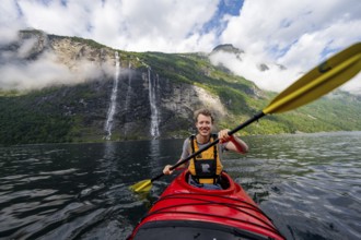 Kayak trip on the Geirangerfjord at the waterfall The Seven Sisters, Young man paddling in a kayak,