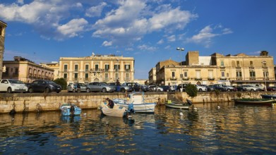 Boats on a waterfront in a town in the warm light and under a blue sky, boat trip around the island