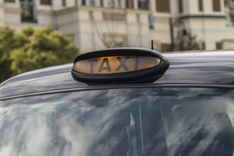Illuminated taxi sign on top of a classic black cab in london, england, providing transportation