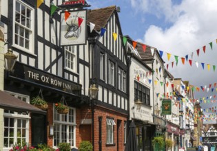 Bunting flags decorating buildings in historic street, The Ox Row Inn and shops, Butcher Row,
