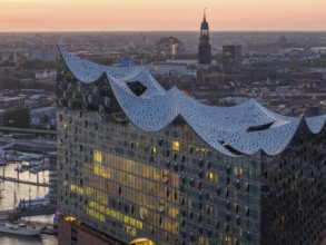 Aerial view of the Elbphilharmonie at sunset with illuminated windows and view over Hamburg and the