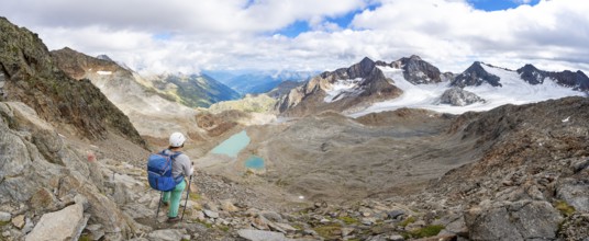 Mountaineer with helmet in high mountain landscape, view of blue glacial lakes, mountain peaks