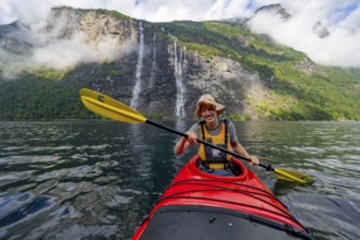 Kayak trip on the Geirangerfjord at the waterfall The Seven Sisters, Young man paddling in a kayak,