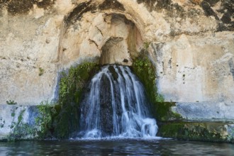 Nymph grotto, Small waterfall flowing from a rocky cave with moss growth, Neapolis Archaeological