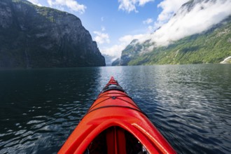 Kayak trip on the Geirangerfjord, tip of a red kayak in the fjord with reflection, atmospheric