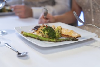 Gourmet plate with fish and broccoli is served on a laid table, event and wedding location Kloster