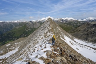 Mountaineer climbing to the summit of Böses Weibl, view of mountain landscape with snow-covered