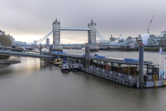 Tower bridge standing majestically over the river thames with boats moored at a pier, showcasing