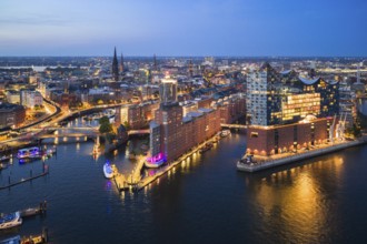Aerial view of the Elbphilharmonie at blue hour with illuminated windows and view over the