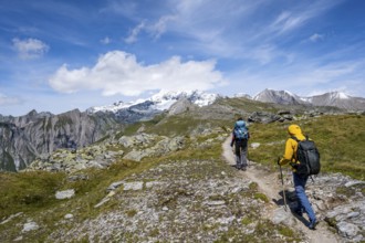 Mountaineers on a hiking trail, view of picturesque mountain landscape with snow-covered summit of