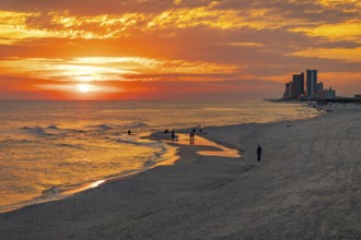 People playing and fishing on the beach at sunset on the Gulf of Mexico at Gulf Shores, Alabama
