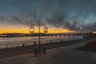 Scenic view of bordeaux cityscape illuminating at sunset over garonne river with pont de pierre