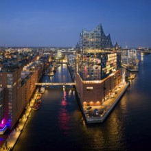 Aerial view of the Elbphilharmonie at blue hour with illuminated windows and view over the