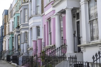 Pastel colored victorian terraced houses with ornate wrought iron fences create a picturesque